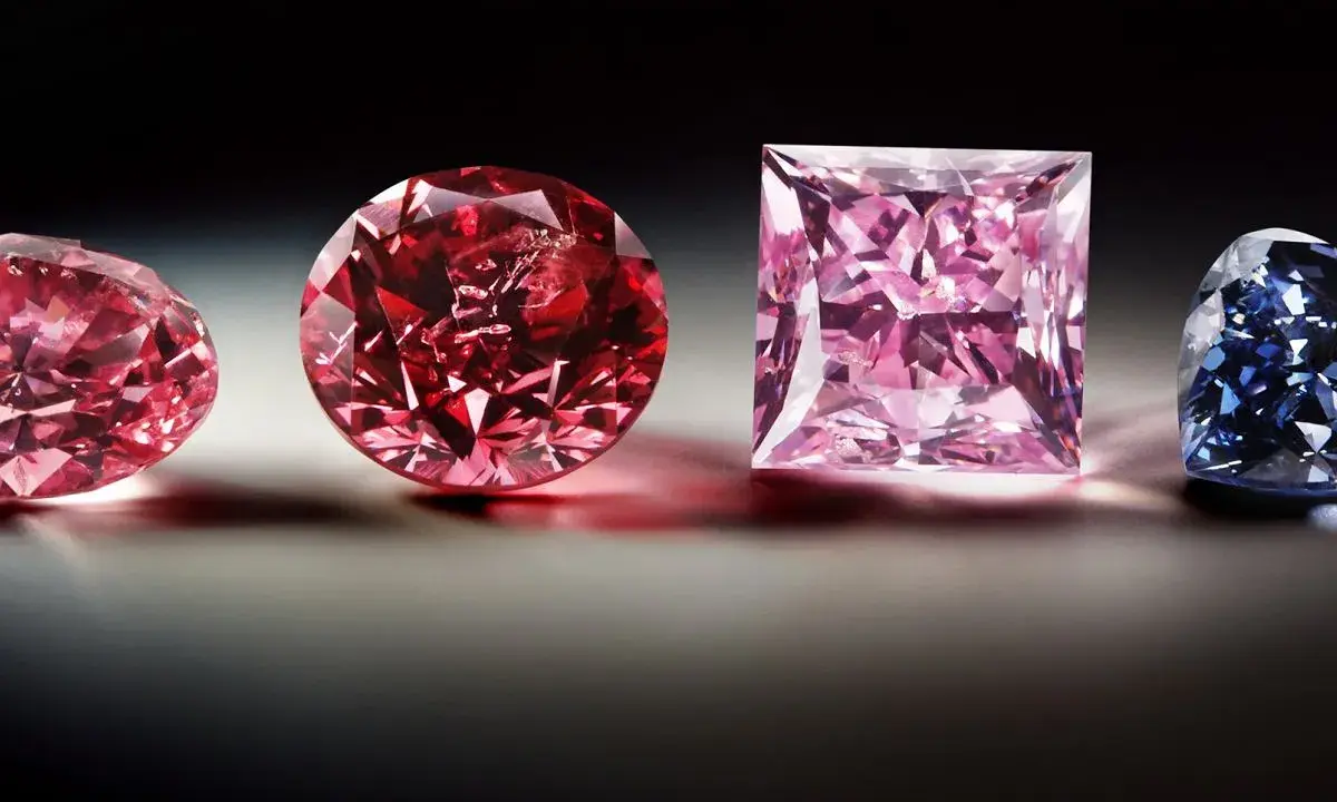 Różowe i czerwone diamenty, jak z polskiej kopalni diamentów, lśnią obok niebieskiego kamienia.