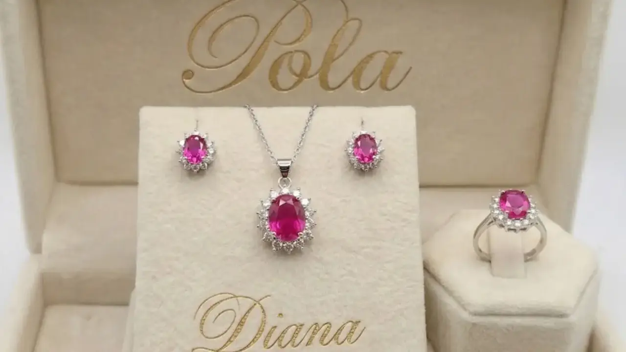 Elegancki komplet biżuterii z różowym korundem i białymi kamieniami, w tym kolczyki, naszyjnik i pierścionek, w beżowym pudełku z napisem "Diana".