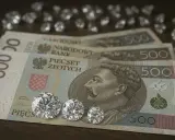 Trzy błyszczące diamenty inwestycyjne leżą na banknotach 500 zł.