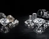 Błyszczące diamenty syntetyczne obok surowych kamieni i cylindrycznych próbek.