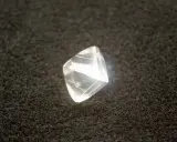 Surowy diament przed szlifowaniem, błyszczący na czarnym tle.