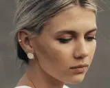 Delikatny kolczyk w lewym uchu, ozdobiony małym kamieniem, dodaje subtelnego blasku.