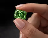 Dłoń trzyma lśniący, prostokątny zielony diament.