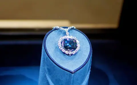Błękitny, wielki diament Hope, otoczony mniejszymi kamieniami, spoczywa na niebieskim aksamitnym postumencie.