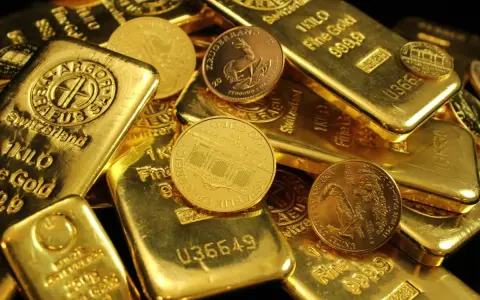 Złote sztabki i monety, niektóre z napisem "1 KILO Fine Gold".