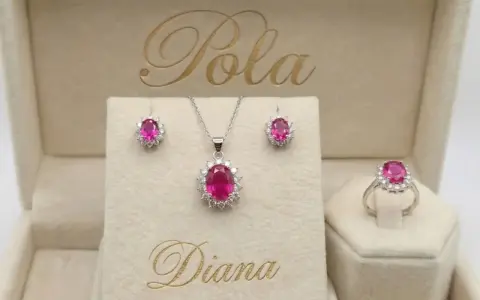 Elegancki komplet biżuterii z różowym korundem i białymi kamieniami, w tym kolczyki, naszyjnik i pierścionek, w beżowym pudełku z napisem "Diana".