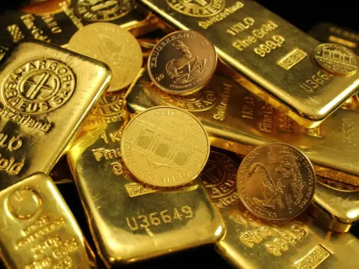 Złote sztabki i monety, niektóre z napisem "1 KILO Fine Gold".