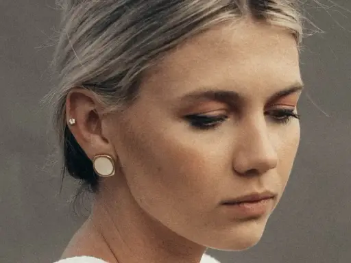 Delikatny kolczyk w lewym uchu, ozdobiony małym kamieniem, dodaje subtelnego blasku.