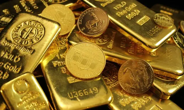 Złote sztabki i monety, niektóre z napisem "1 KILO Fine Gold".