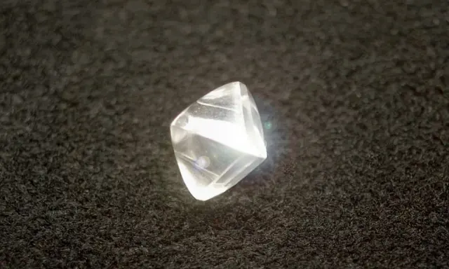 Surowy diament przed szlifowaniem, błyszczący na czarnym tle.