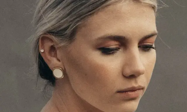 Delikatny kolczyk w lewym uchu, ozdobiony małym kamieniem, dodaje subtelnego blasku.